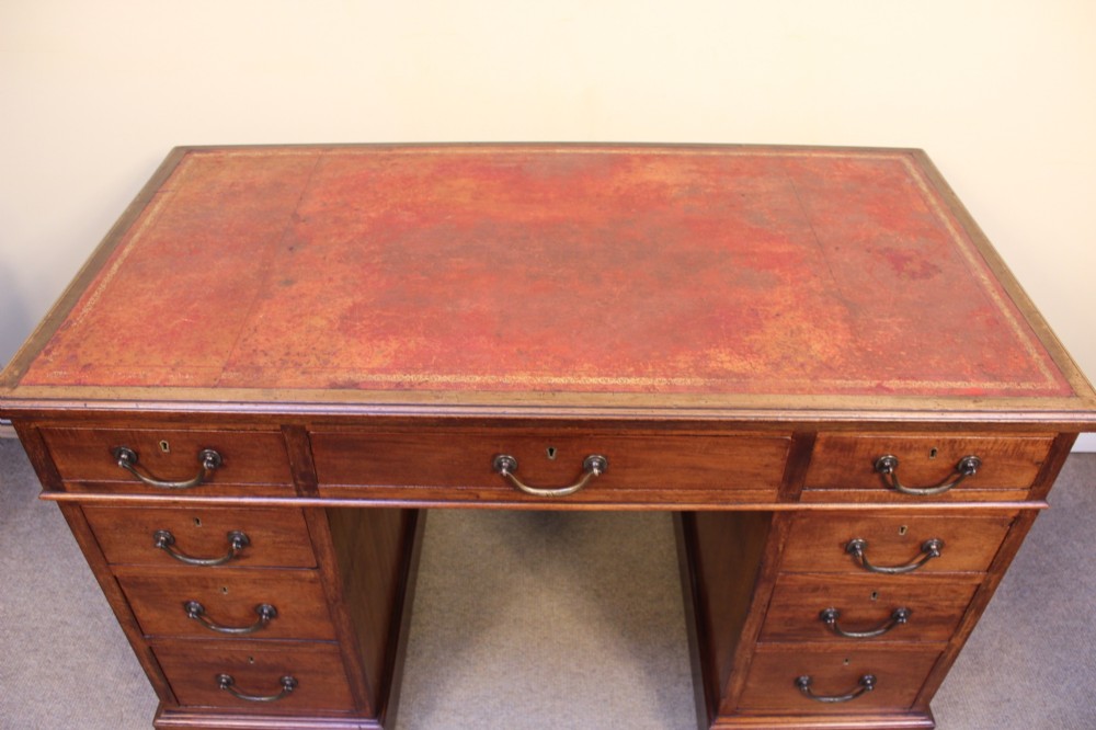 A 19th-century mahogany pedestal desk featuring an inset leather writing top, nine drawers with brass handles, and plinth bases. View IV