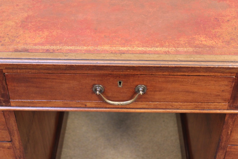 A 19th-century mahogany pedestal desk featuring an inset leather writing top, nine drawers with brass handles, and plinth bases. View VII