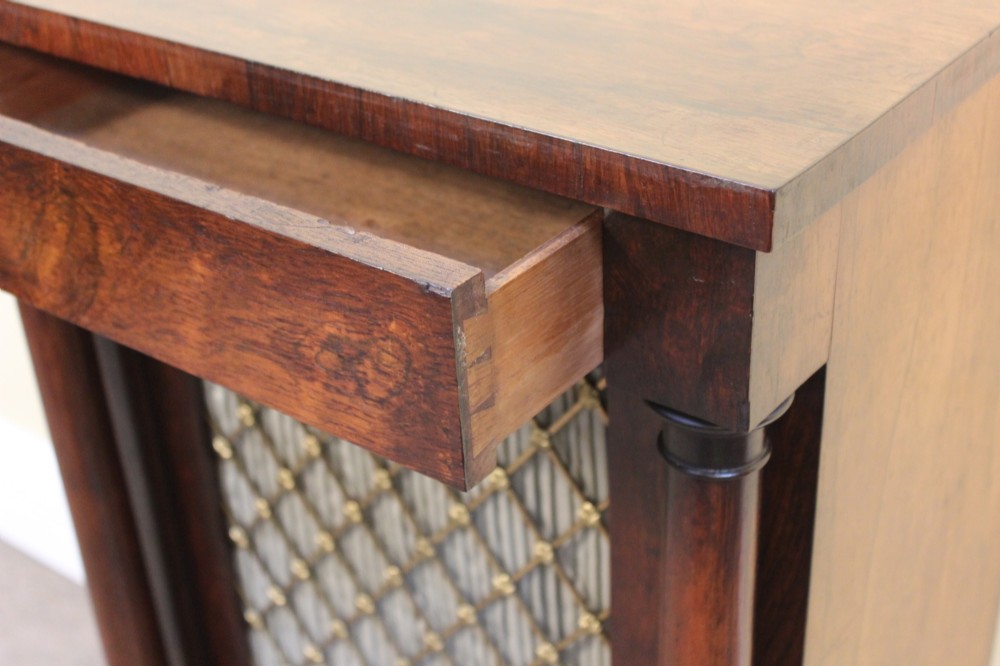 A 19th-century rosewood pier cabinet featuring a single door with a brass wire grille over pleated fabric, flanked by turned columns. View V