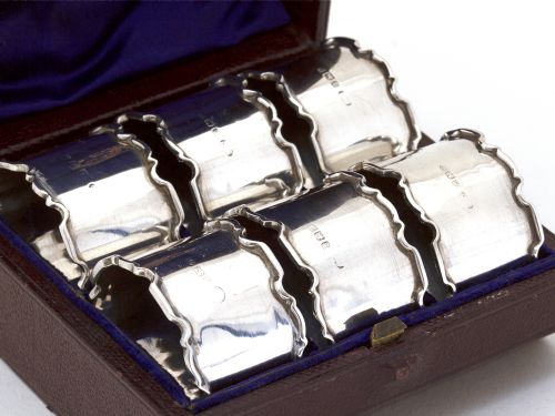 BOXED SET OF SIX SILVER NAPKIN RINGS WITH PLAIN BODIES AND CHIPPENDALE STYLE BORDERS - ADDITIONAL PHOTO 1