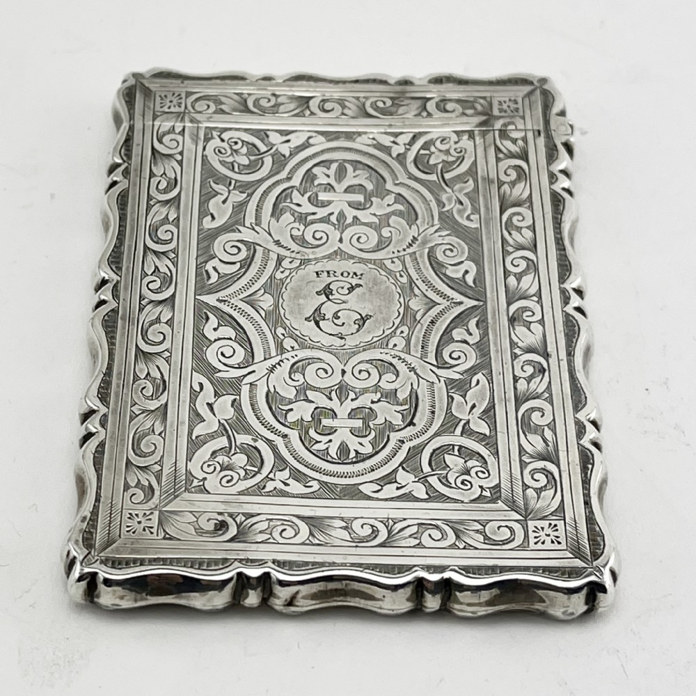 Victorian sterling silver card case featuring intricate foliate hand engraving, scalloped edges, and a central monogrammed cartouche.