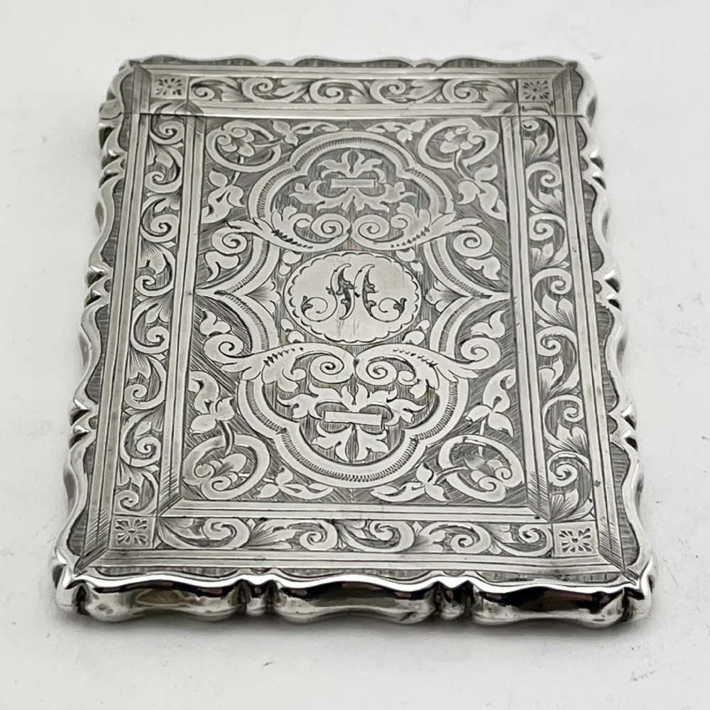Victorian sterling silver card case featuring intricate foliate hand engraving, scalloped edges, and a central monogrammed cartouche. View II