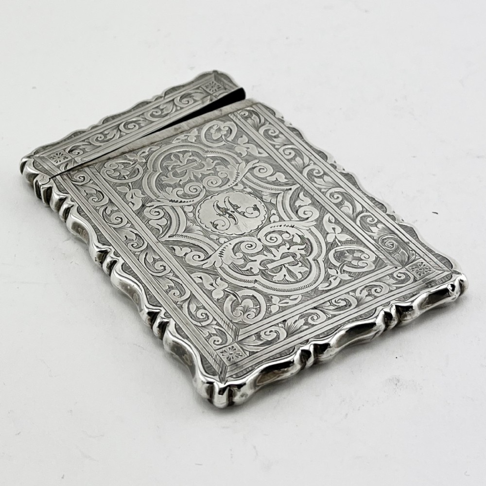 Victorian sterling silver card case featuring intricate foliate hand engraving, scalloped edges, and a central monogrammed cartouche. View IV