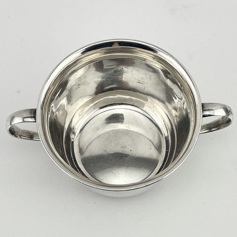 A circular sterling silver porringer featuring two side handles and an engraved decorative band along the rim. View II