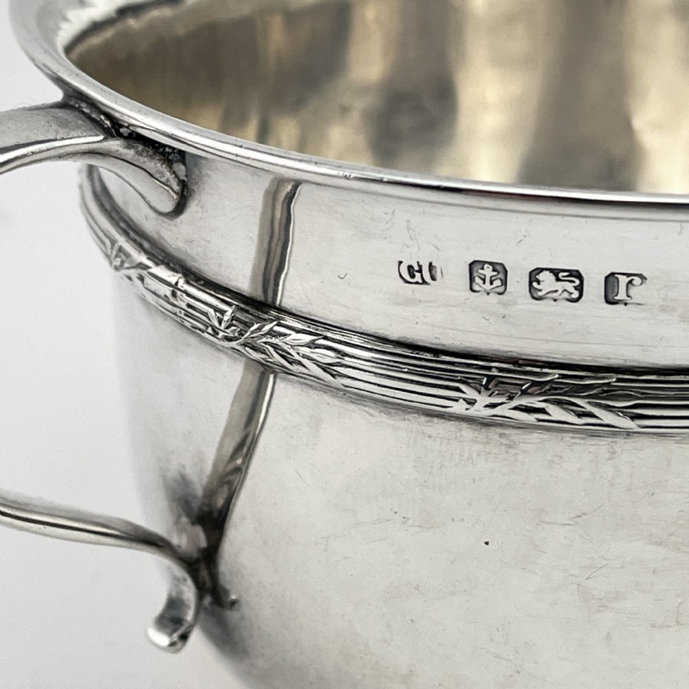 A circular sterling silver porringer featuring two side handles and an engraved decorative band along the rim. View IV