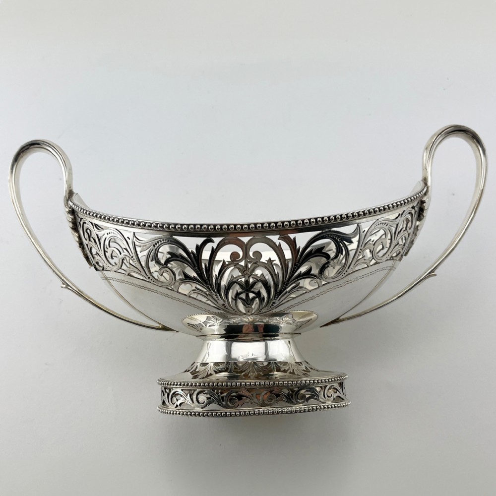 A pair of silver-plated boat-shaped dishes featuring pierced scrollwork borders, high reeded side handles, and oval pedestal bases. View III