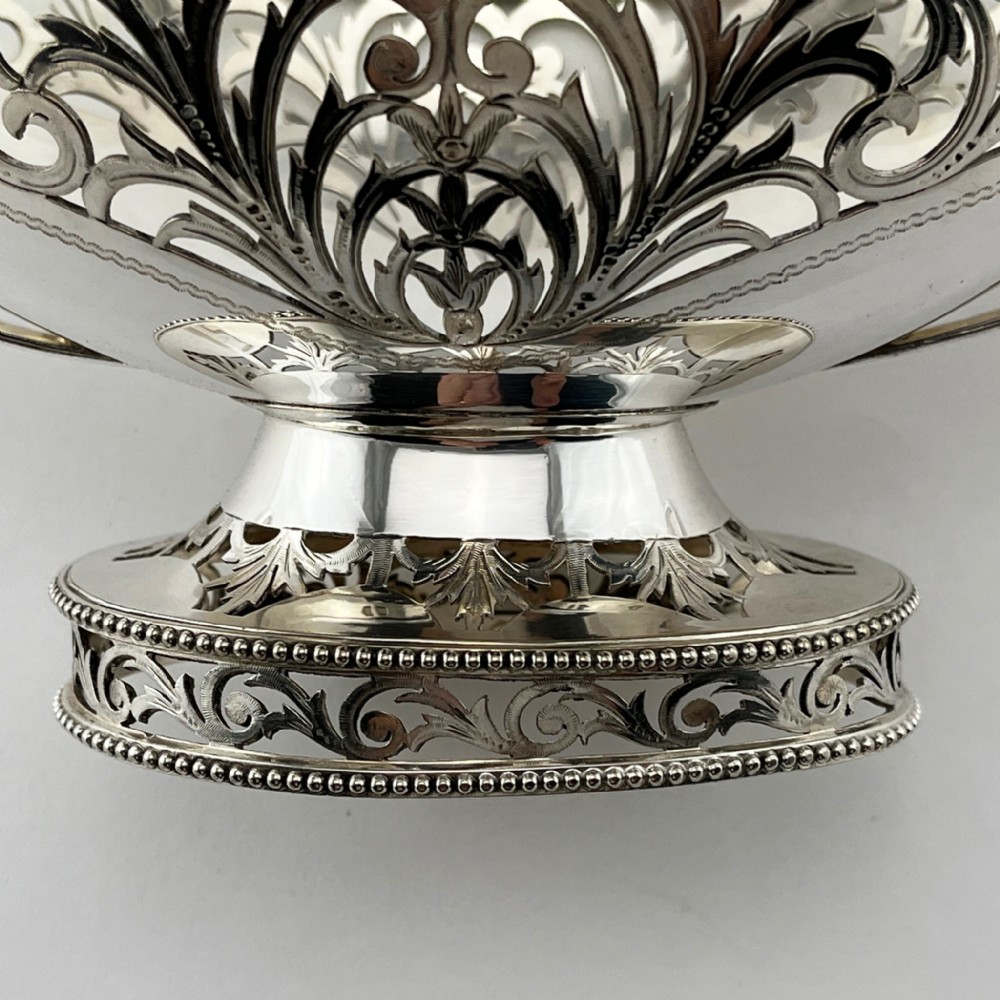 A pair of silver-plated boat-shaped dishes featuring pierced scrollwork borders, high reeded side handles, and oval pedestal bases. View IV