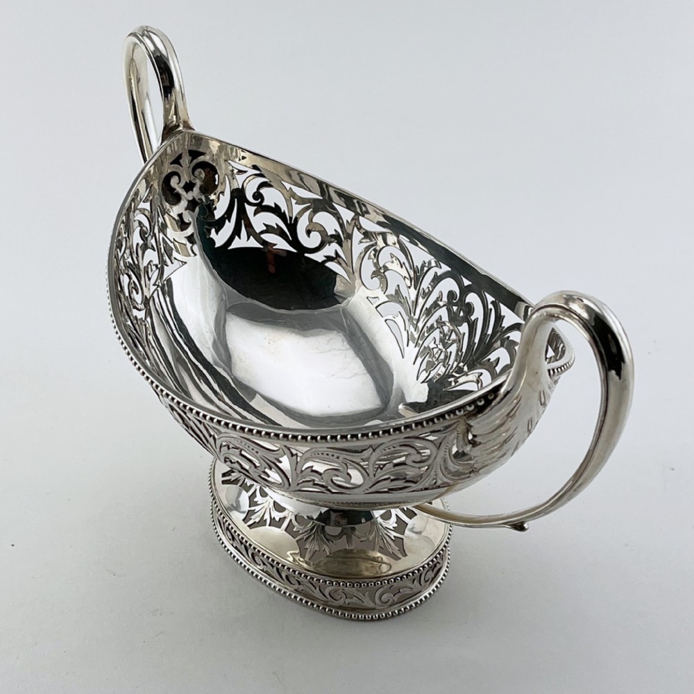 A pair of silver-plated boat-shaped dishes featuring pierced scrollwork borders, high reeded side handles, and oval pedestal bases. View V
