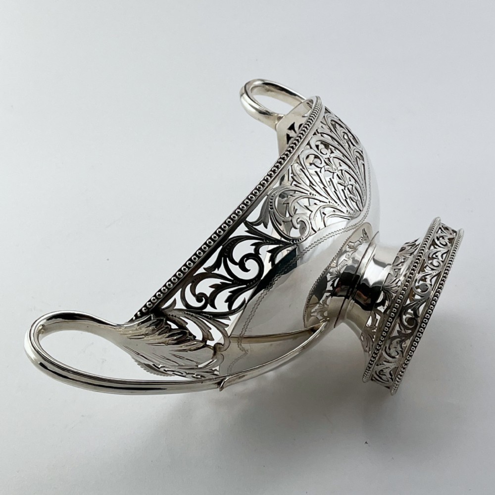 A pair of silver-plated boat-shaped dishes featuring pierced scrollwork borders, high reeded side handles, and oval pedestal bases. View VI