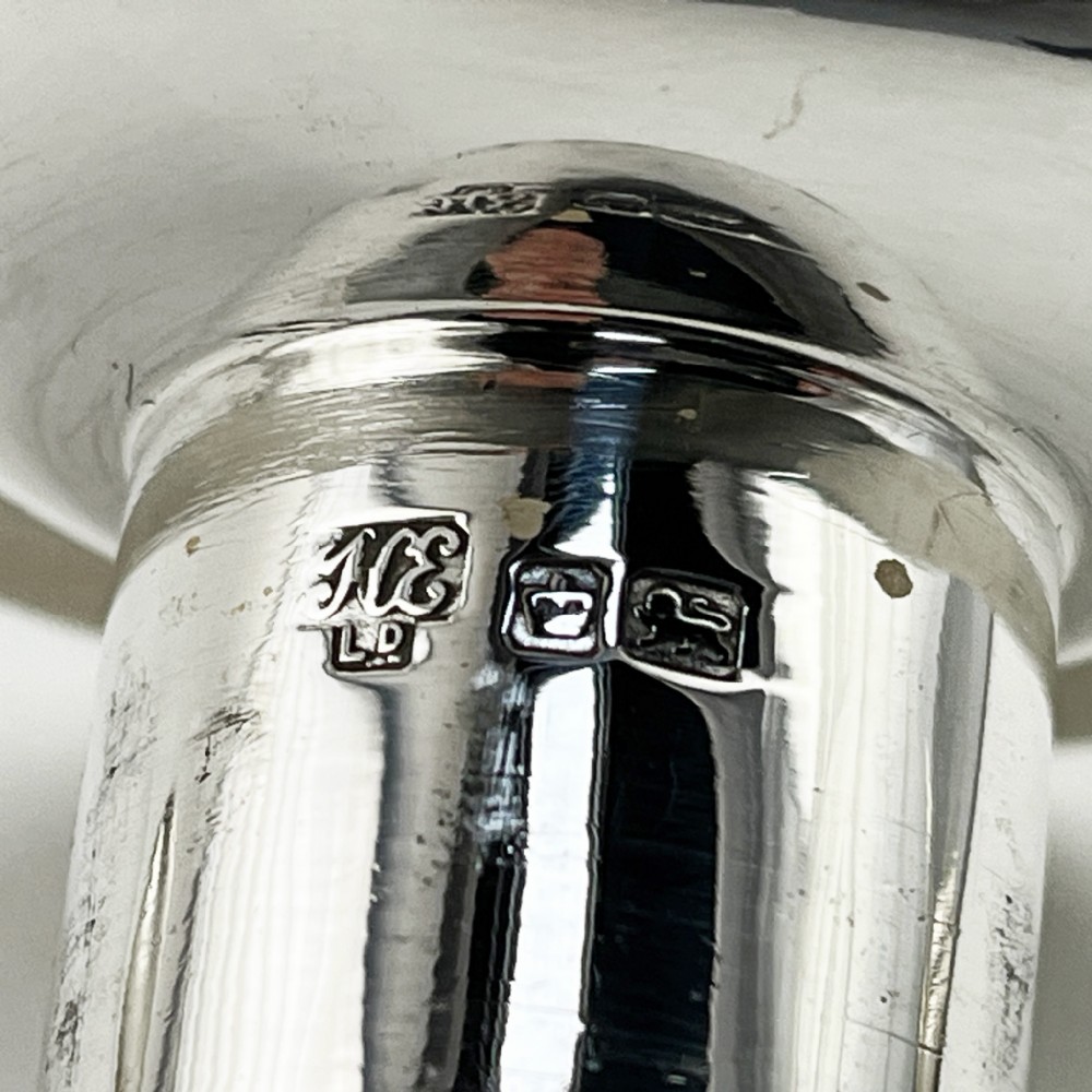 A pair of hallmarked sterling silver candlesticks featuring tapered columns decorated with floral festoons and square stepped bases. View VIII