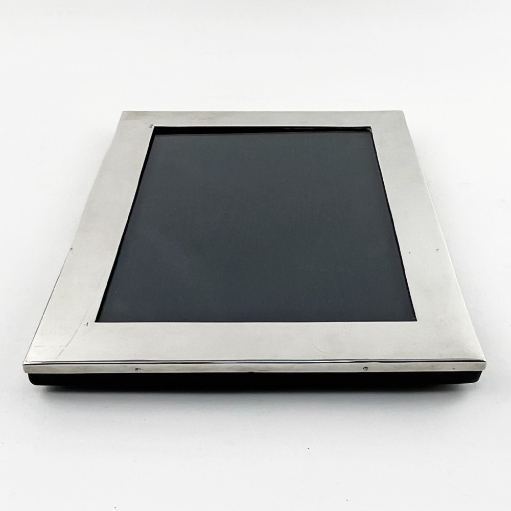 A rectangular sterling silver photo frame with a polished surface, visible hallmarks on the side edge, and a dark backing. View II