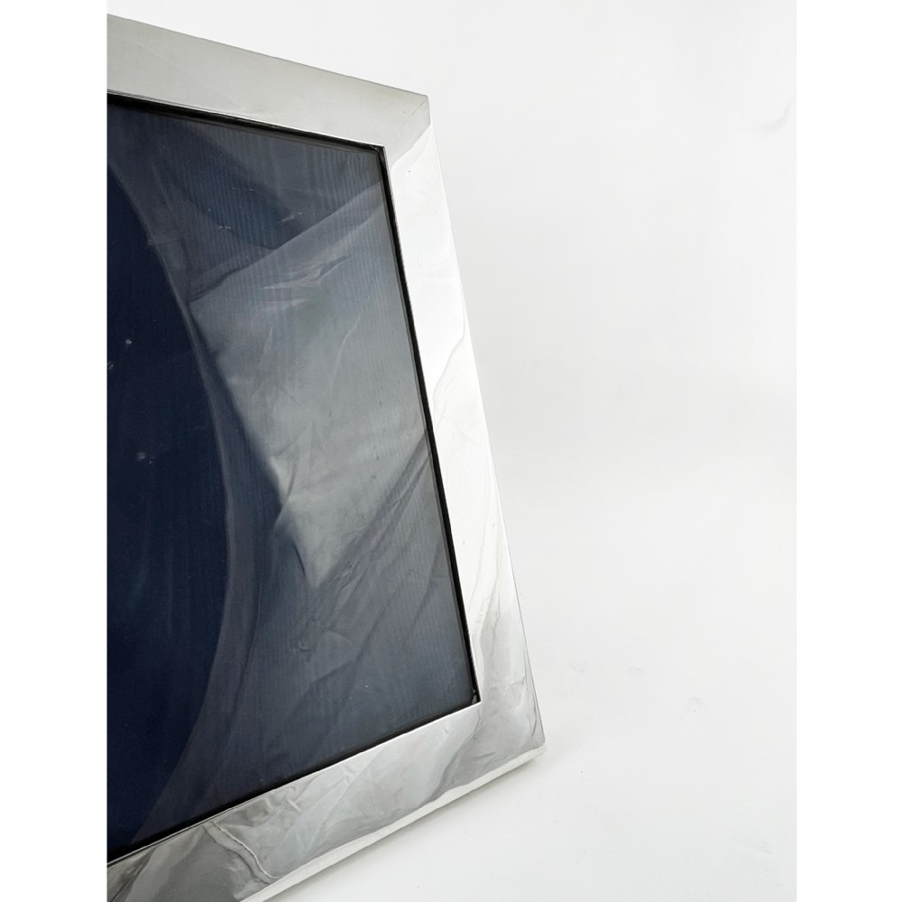 A rectangular sterling silver photo frame with a polished surface, visible hallmarks on the side edge, and a dark backing. View IV