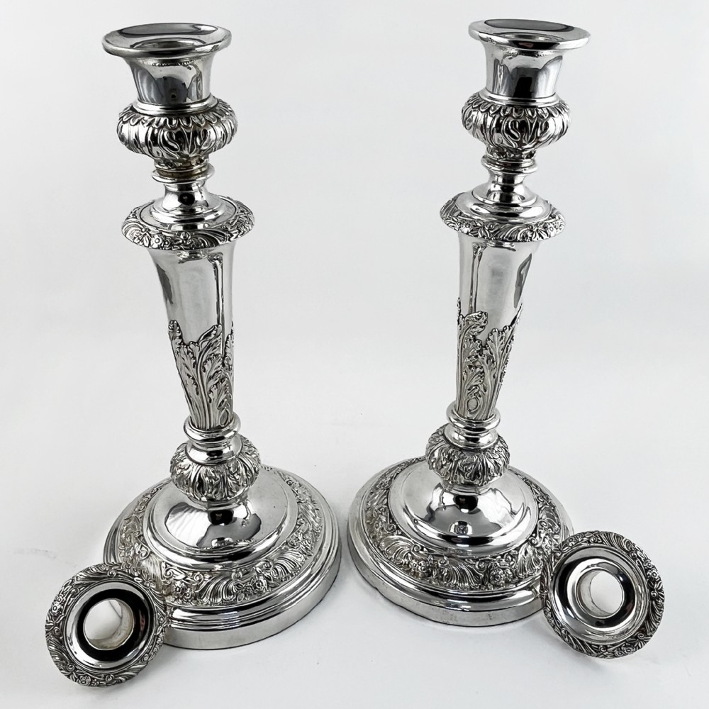 A pair of antique silver-plated candlesticks featuring acanthus leaf motifs, knopped stems, and broad circular bases. View V