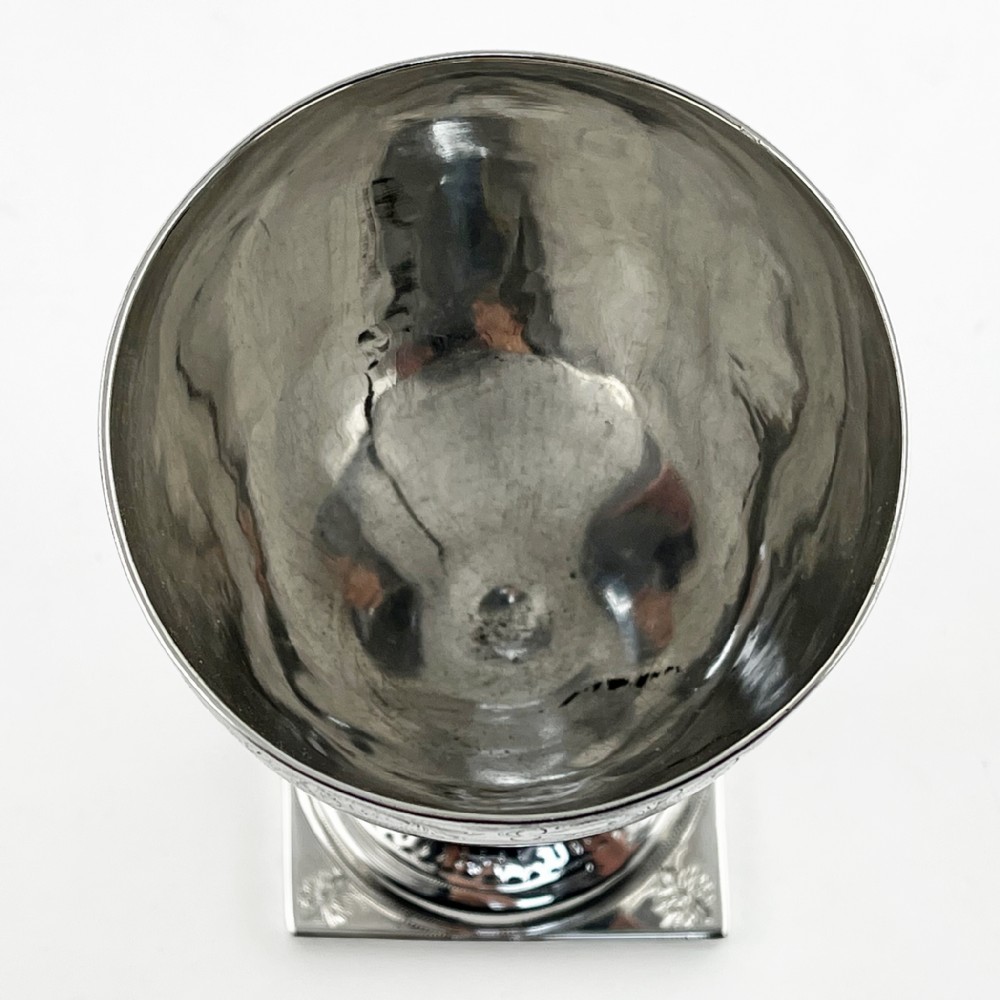 A Georgian sterling silver goblet featuring a vase-shaped bowl with engraved crest and foliate border set upon a square plinth base. View IV
