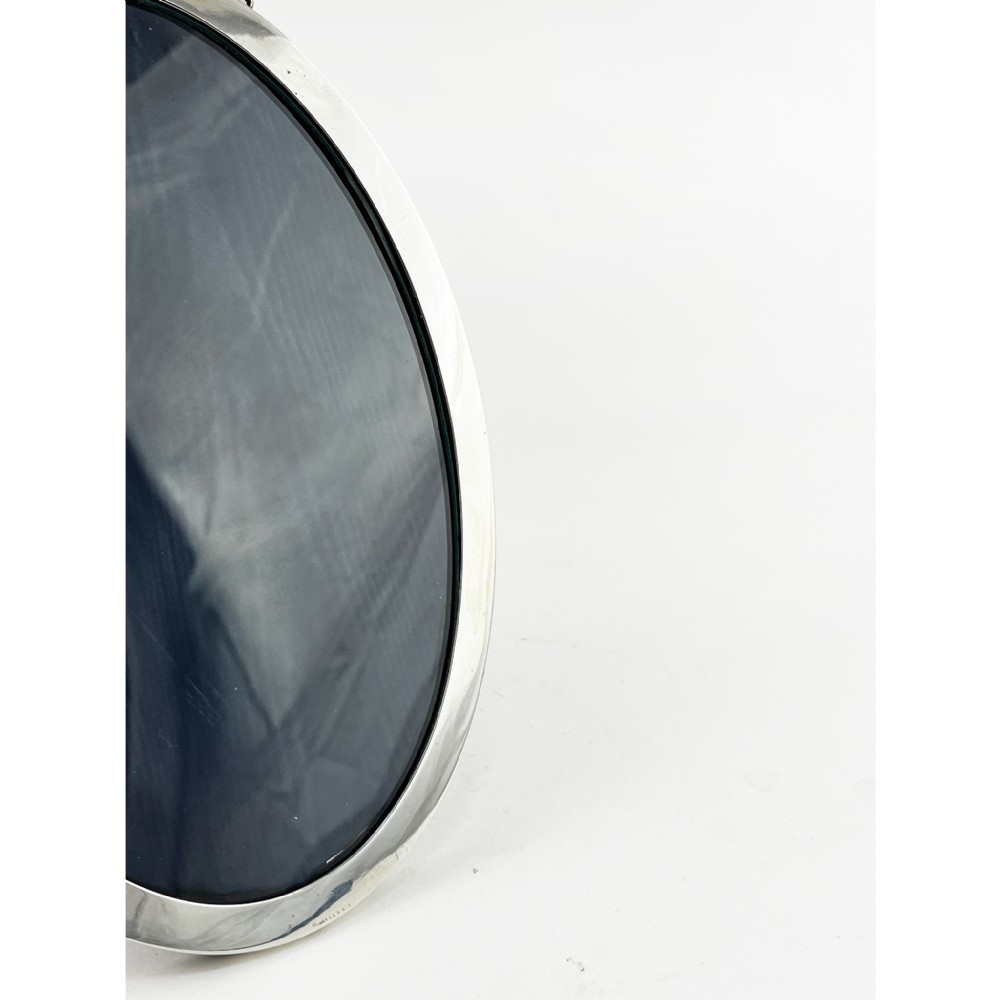 An oval sterling silver photo frame with a decorative ribbon crest at the top and an easel back stand. View II