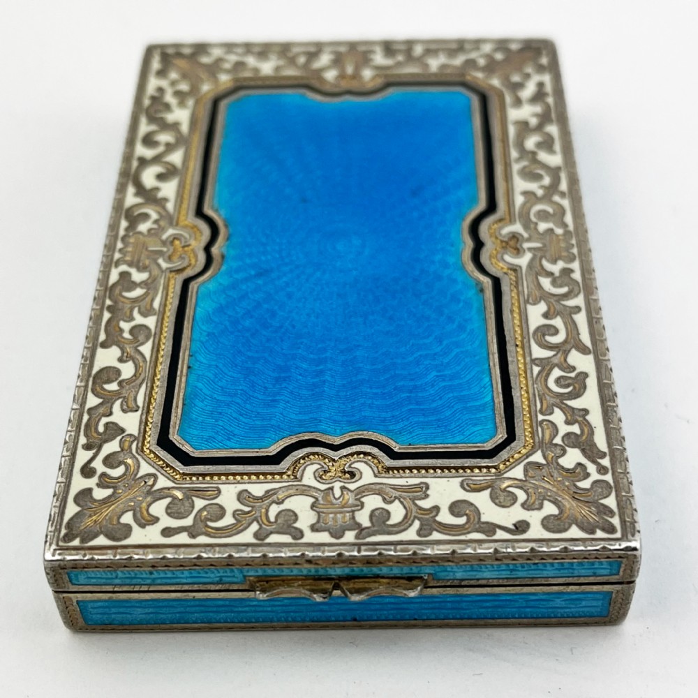 A rectangular sterling silver card case featuring bright blue guilloche enamel framed by white scroll enamel and silver gilt borders. View II