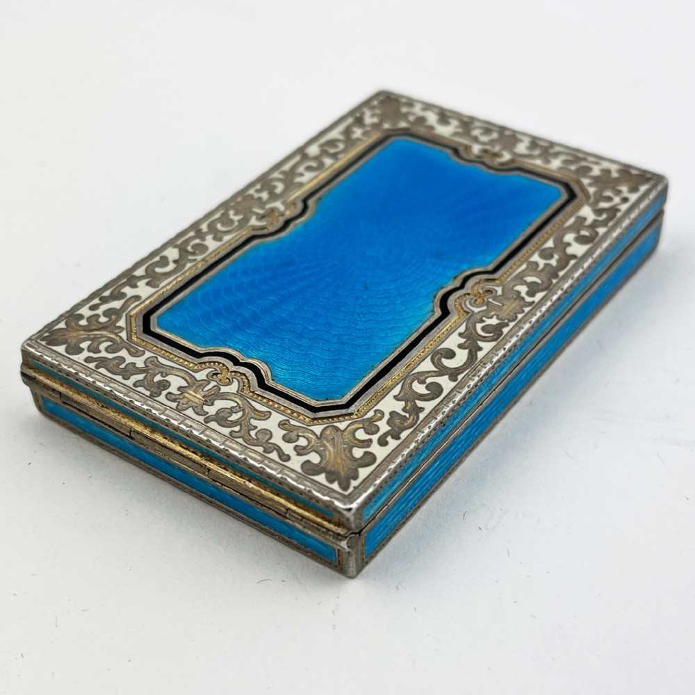 A rectangular sterling silver card case featuring bright blue guilloche enamel framed by white scroll enamel and silver gilt borders. View III