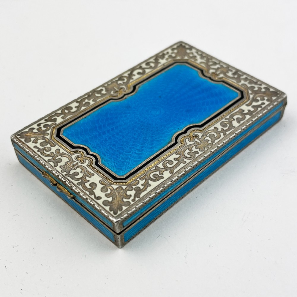 A rectangular sterling silver card case featuring bright blue guilloche enamel framed by white scroll enamel and silver gilt borders. View IV