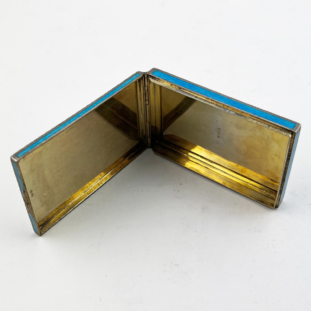 A rectangular sterling silver card case featuring bright blue guilloche enamel framed by white scroll enamel and silver gilt borders. View V