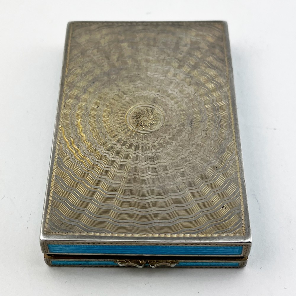 A rectangular sterling silver card case featuring bright blue guilloche enamel framed by white scroll enamel and silver gilt borders. View VI