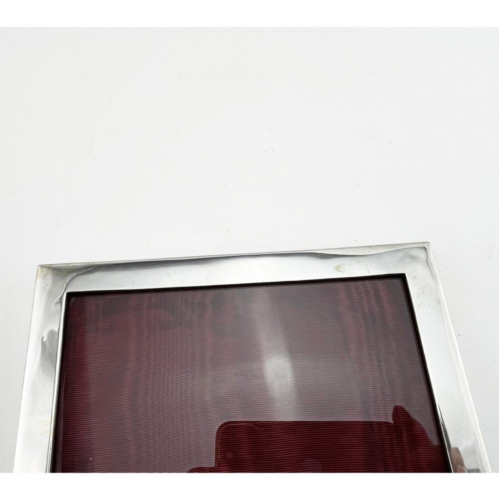 A rectangular sterling silver photo frame with a polished plain border standing vertically on an easel back. View V