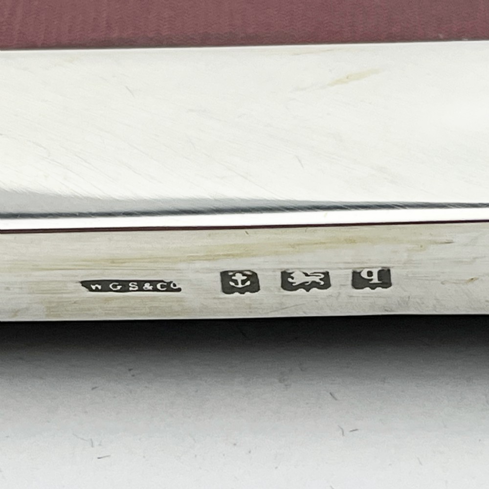 A rectangular sterling silver photo frame with a polished plain border standing vertically on an easel back. View VI