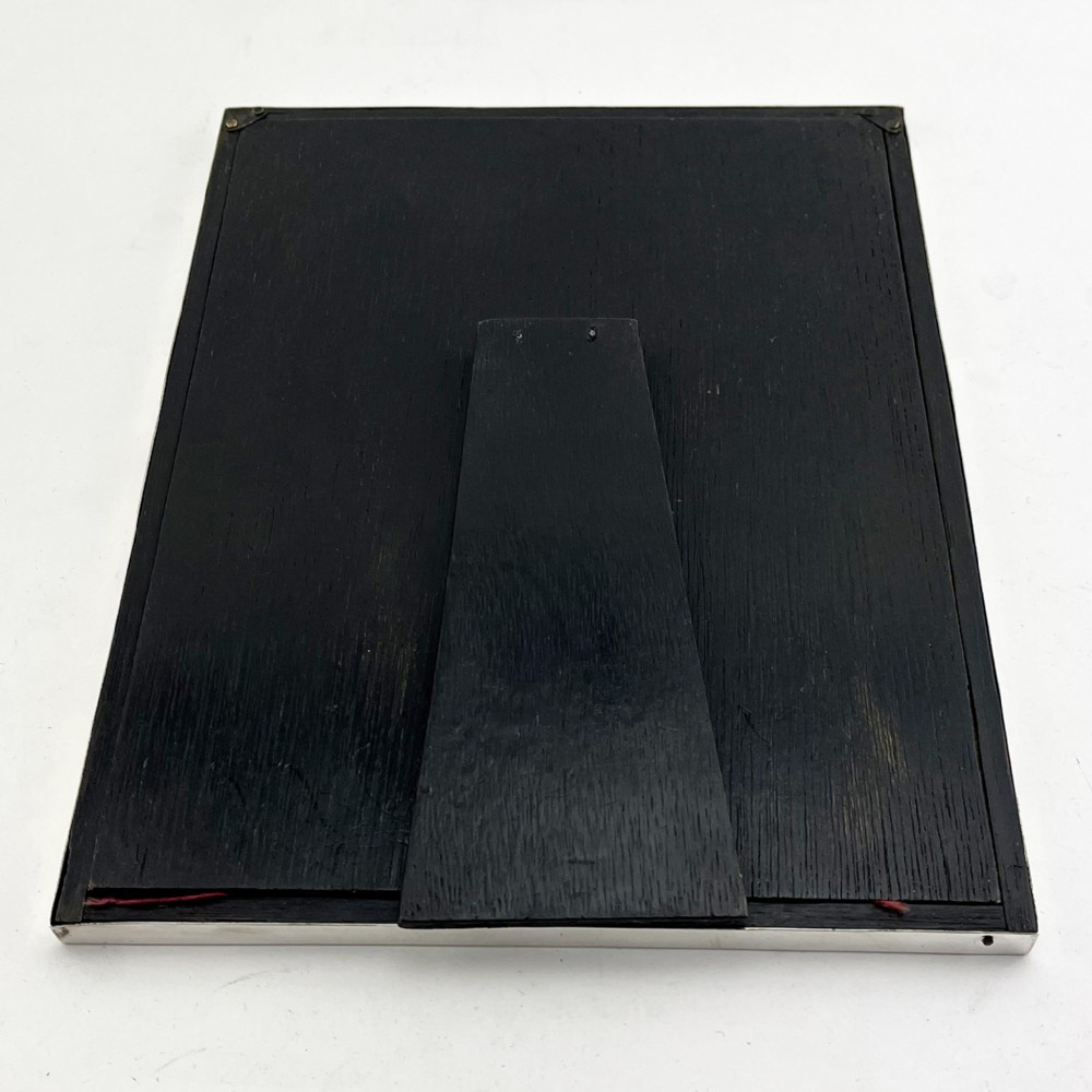 A rectangular sterling silver photo frame with a polished plain border standing vertically on an easel back. View VII
