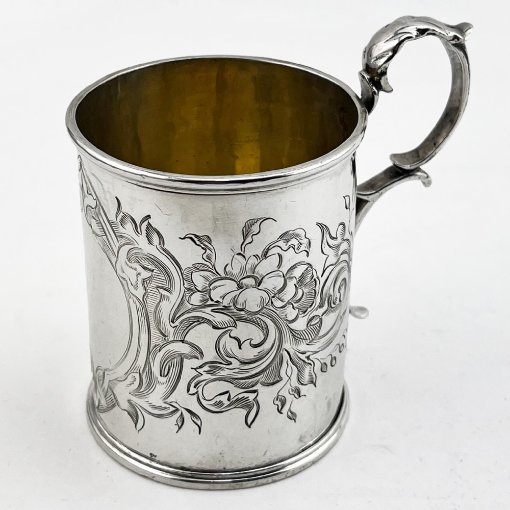 A Victorian sterling silver christening mug featuring floral engraving and a silver-gilt interior.