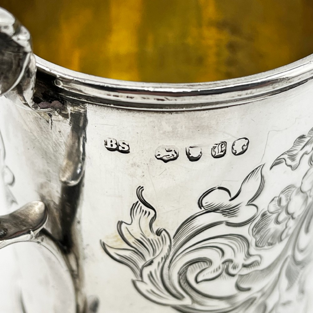 A Victorian sterling silver christening mug featuring floral engraving and a silver-gilt interior. View V