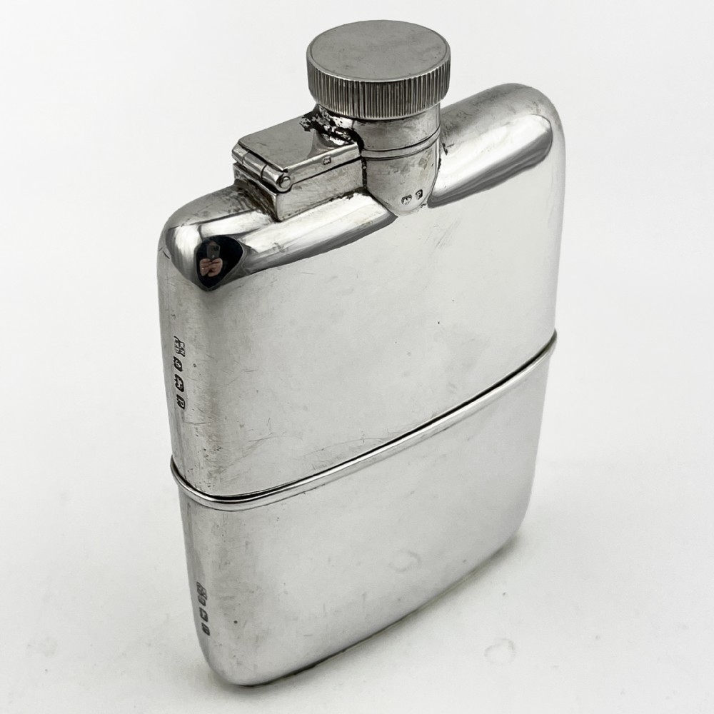 A curved sterling silver hip flask with a hinged screw cap and hallmarks stamped along the side.