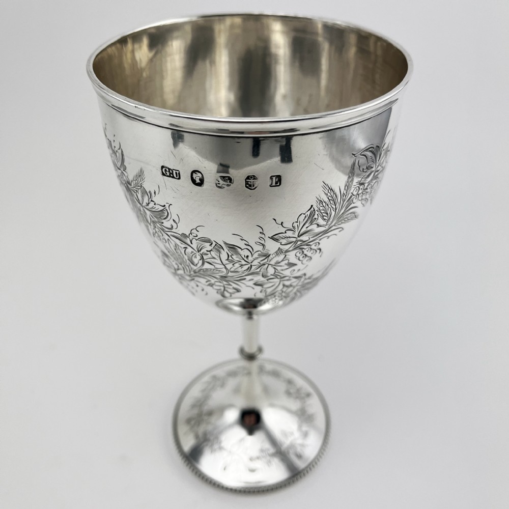 A Victorian sterling silver goblet featuring detailed floral foliage engraving around the bowl, a central knopped stem, and an engraved circular base. View II