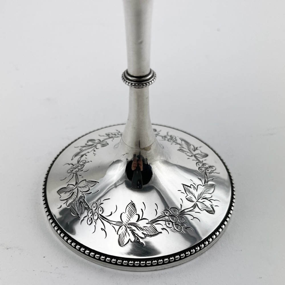 A Victorian sterling silver goblet featuring detailed floral foliage engraving around the bowl, a central knopped stem, and an engraved circular base. View V