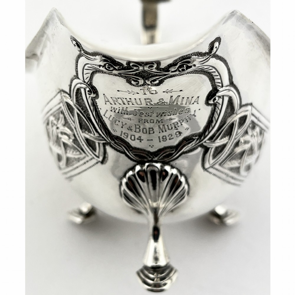 An Irish sterling silver sauce boat decorated with chased Celtic knotwork, featuring a scroll handle and three hoof feet. View V