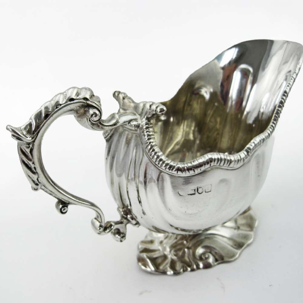 A pair of polished sterling silver sauce boats featuring fluted bodies, scroll handles, and decorated pedestal bases. View III