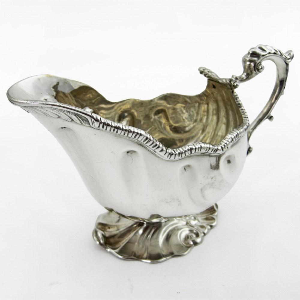 A pair of polished sterling silver sauce boats featuring fluted bodies, scroll handles, and decorated pedestal bases. View IV