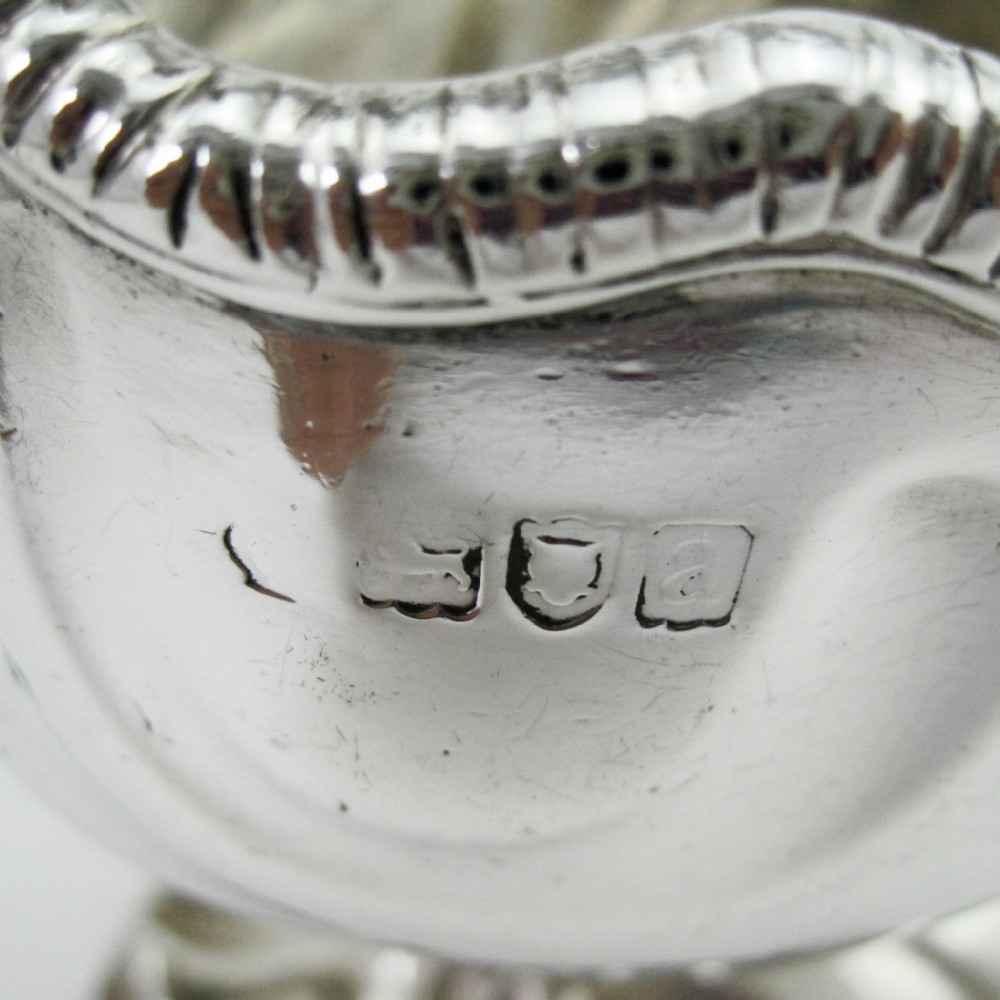 A pair of polished sterling silver sauce boats featuring fluted bodies, scroll handles, and decorated pedestal bases. View VI