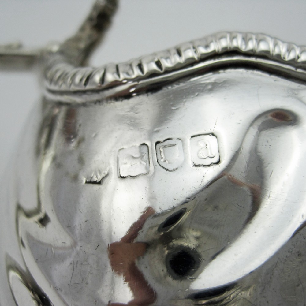 A pair of polished sterling silver sauce boats featuring fluted bodies, scroll handles, and decorated pedestal bases. View VII