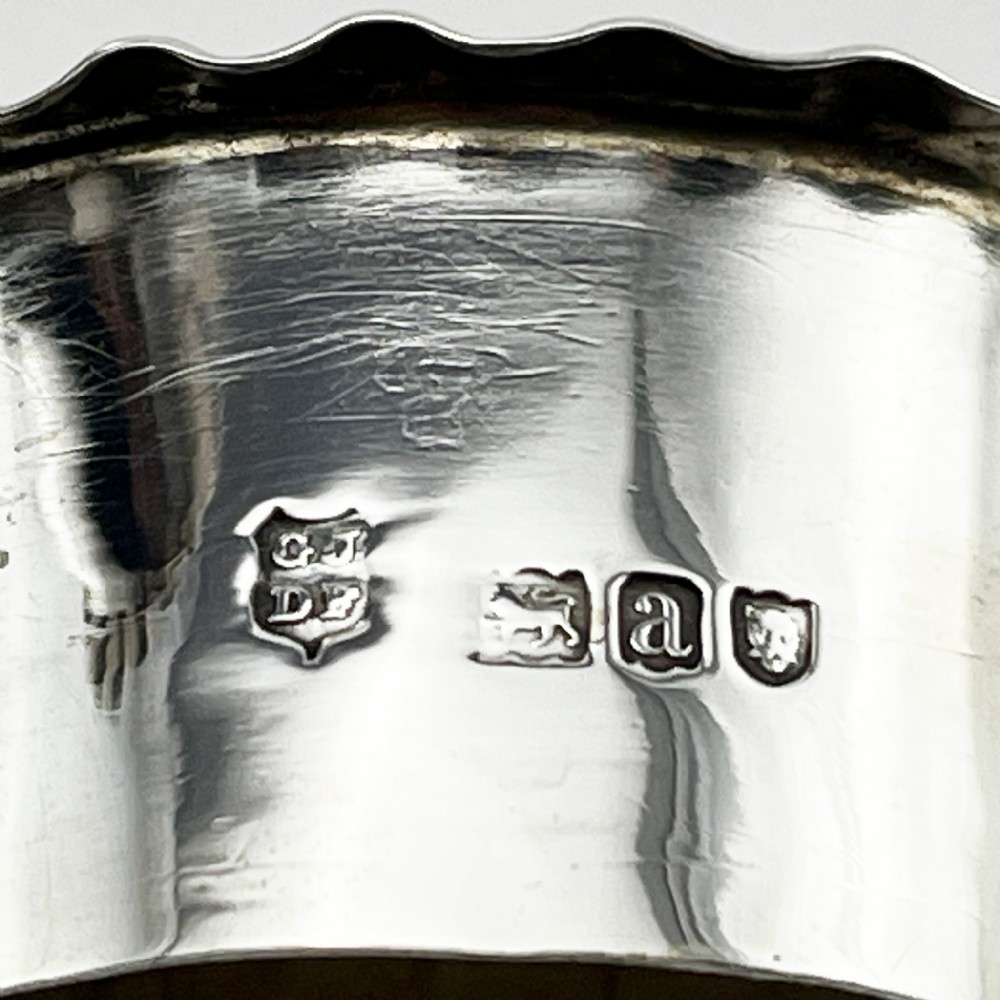 An oval Victorian sterling silver tea caddy featuring chased scrollwork decoration, a blank central cartouche, a scalloped border, and a pull-off cap lid. View VI