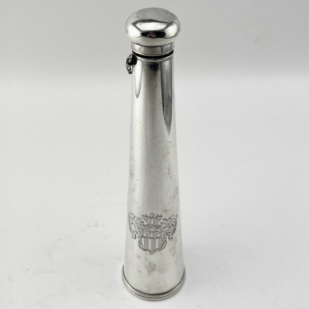 A conical Victorian sterling silver hunting saddle flask featuring an engraved coat of arms and a rounded silver cap.