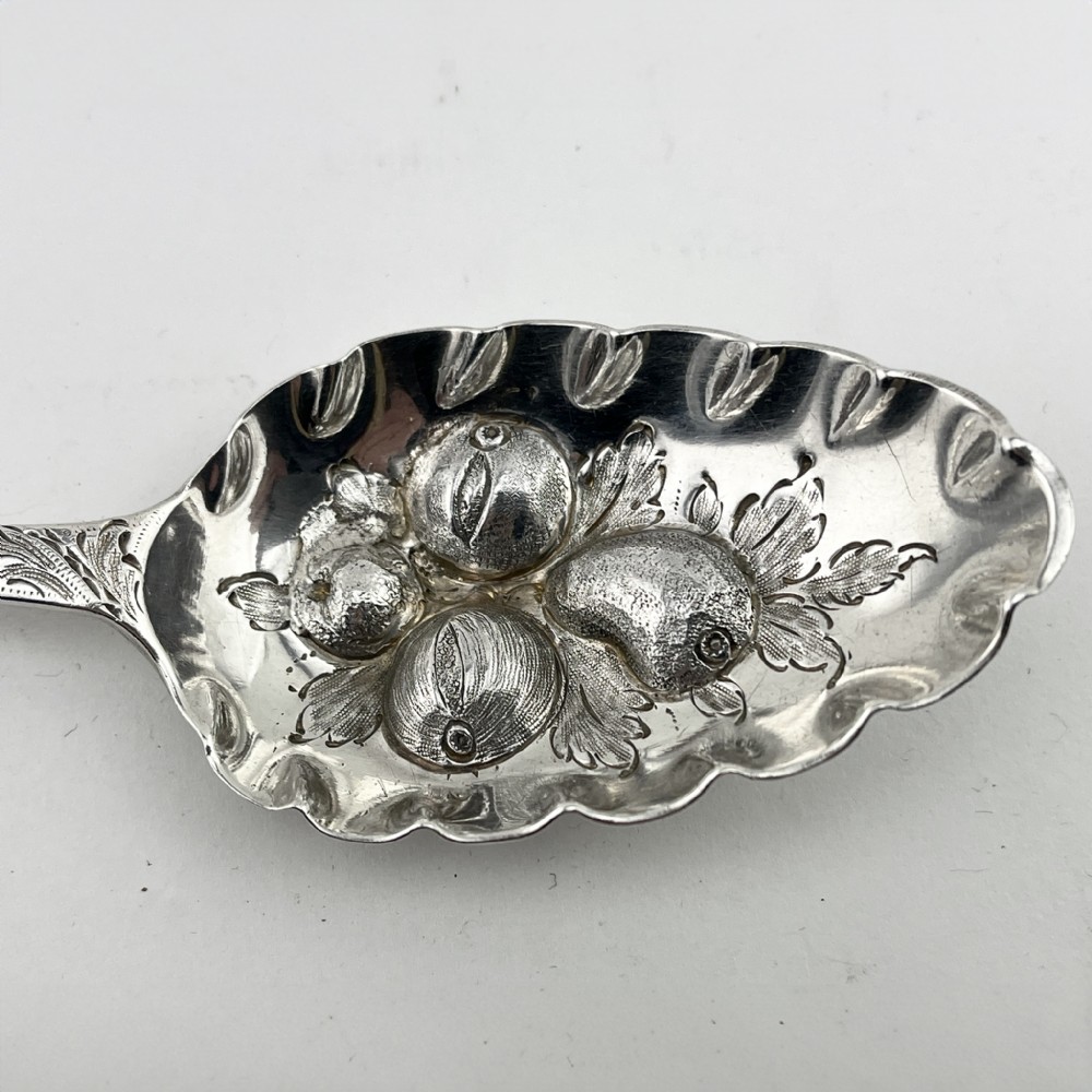 A pair of George III sterling silver berry spoons with fruit embossed bowls and chased handles, presented in a black velvet and purple silk lined case. View III