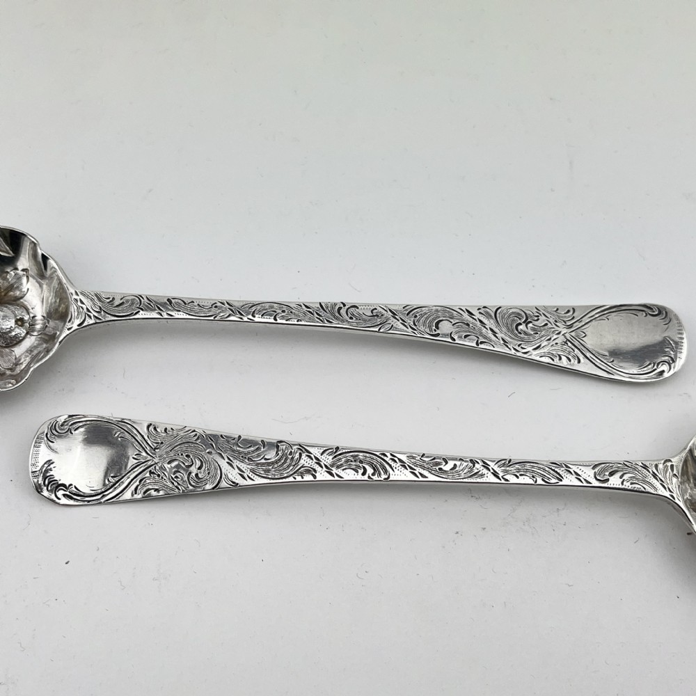 A pair of George III sterling silver berry spoons with fruit embossed bowls and chased handles, presented in a black velvet and purple silk lined case. View IV