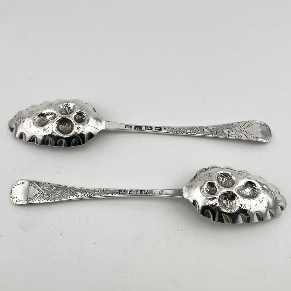 A pair of George III sterling silver berry spoons with fruit embossed bowls and chased handles, presented in a black velvet and purple silk lined case. View V