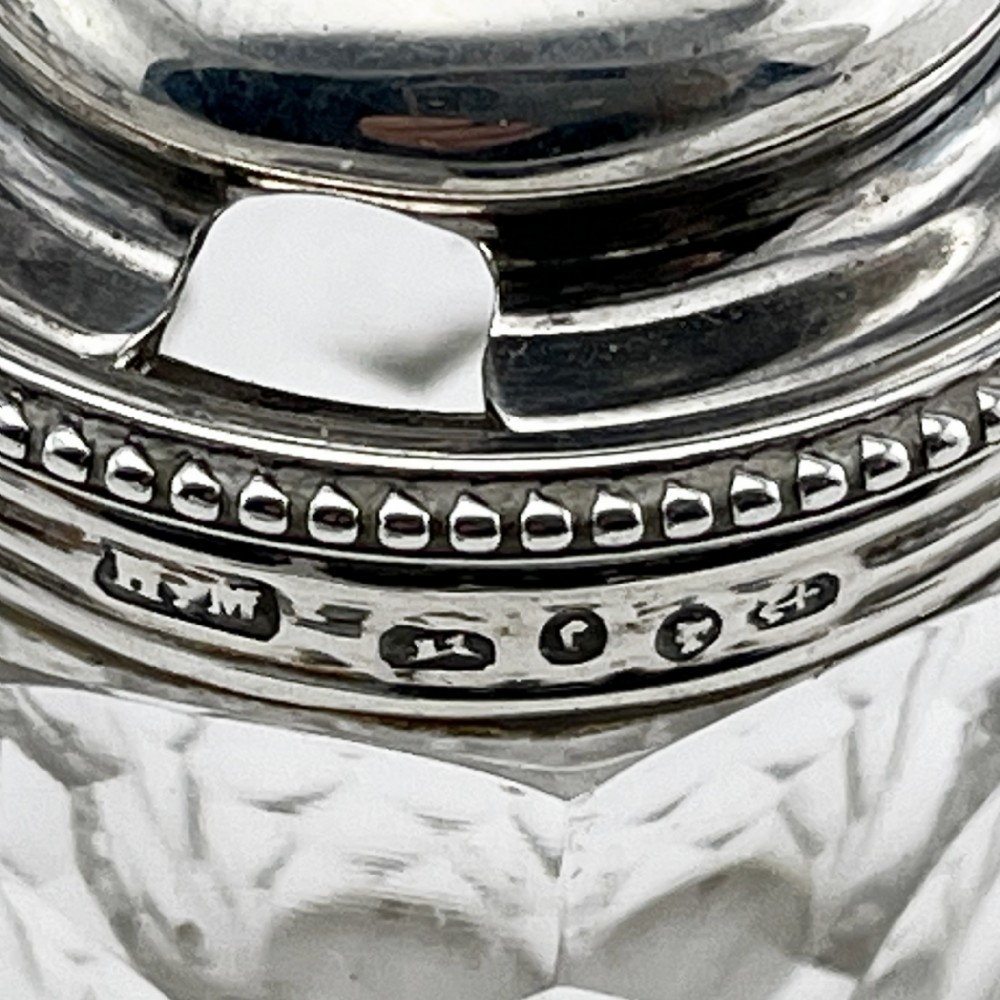 A Victorian sterling silver cruet stand holding four cut glass vessels with silver mounts, featuring shell feet and a central handle. View VII