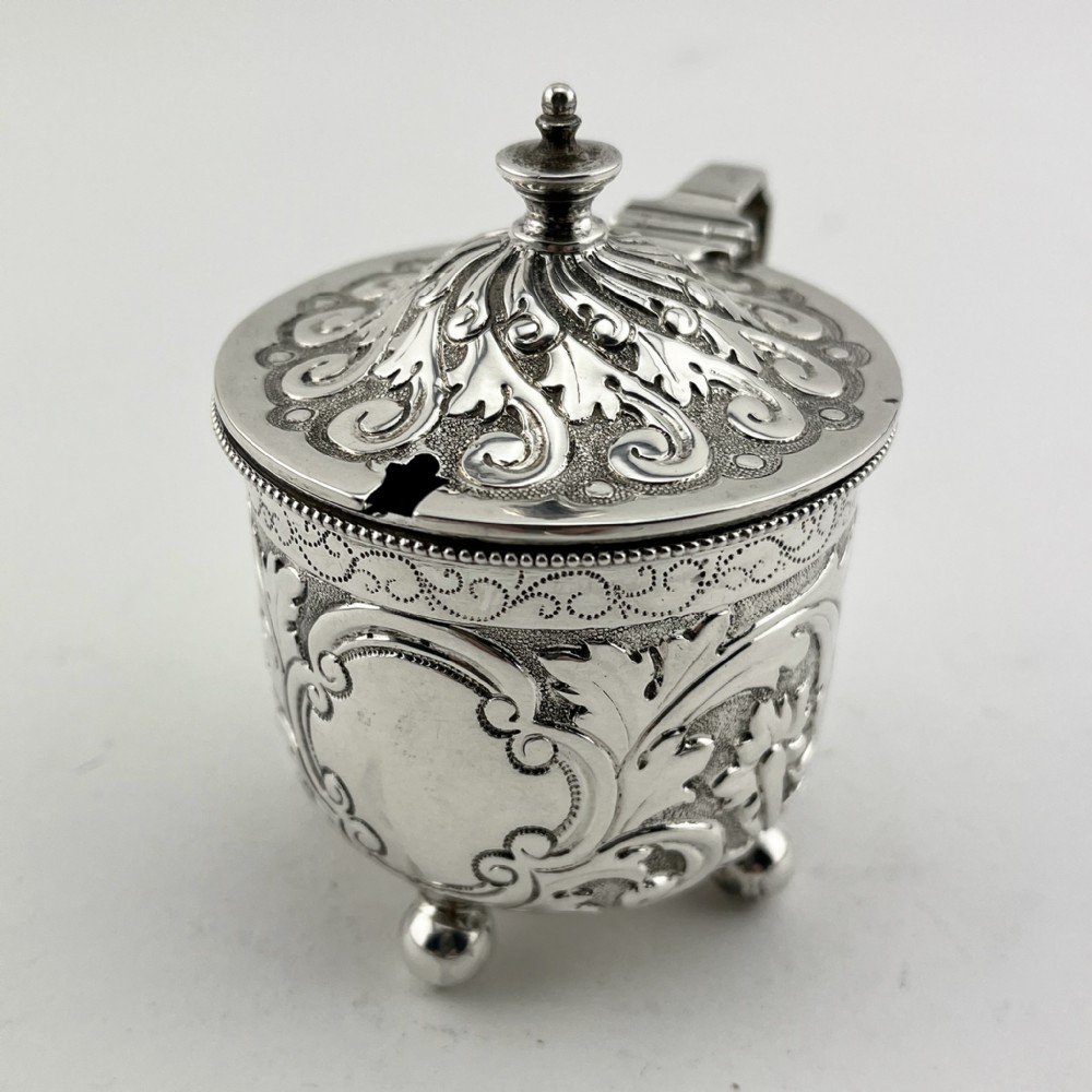 A Victorian sterling silver three-piece condiment set with floral repousse engraving housed inside an open velvet-lined presentation case. View IV