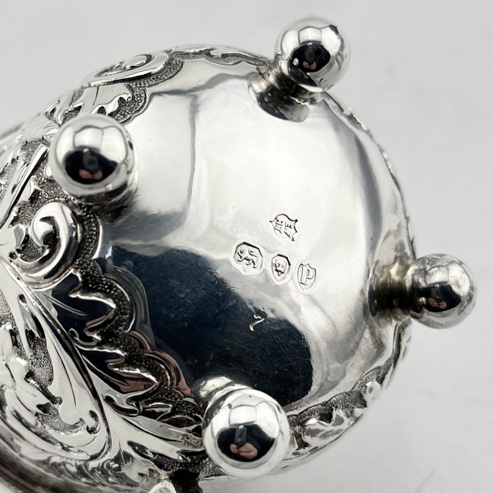 A Victorian sterling silver three-piece condiment set with floral repousse engraving housed inside an open velvet-lined presentation case. View VI