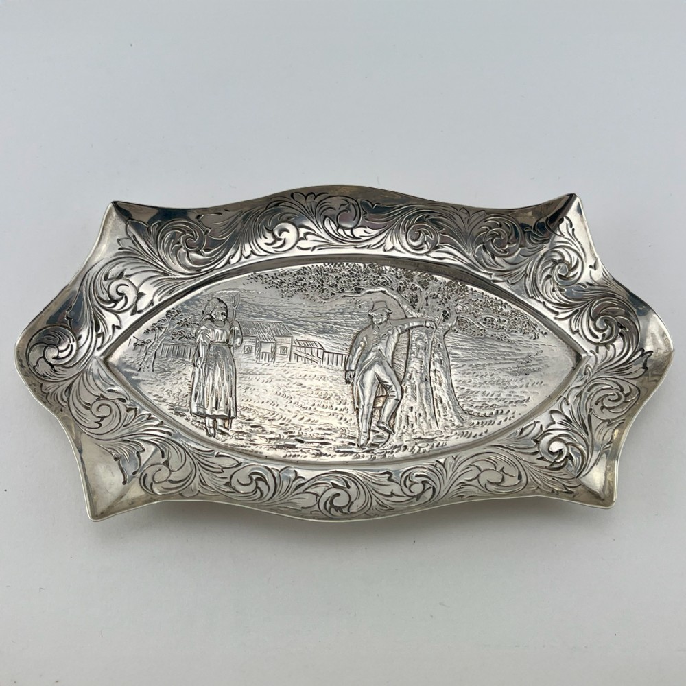 A pair of Victorian sterling silver dishes featuring relief-embossed pastoral scenes with ornate scrolled borders. View II