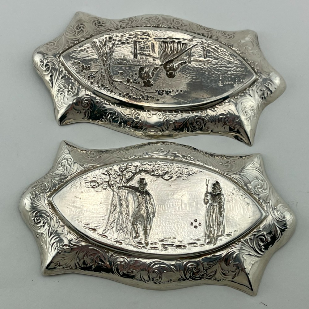 A pair of Victorian sterling silver dishes featuring relief-embossed pastoral scenes with ornate scrolled borders. View III