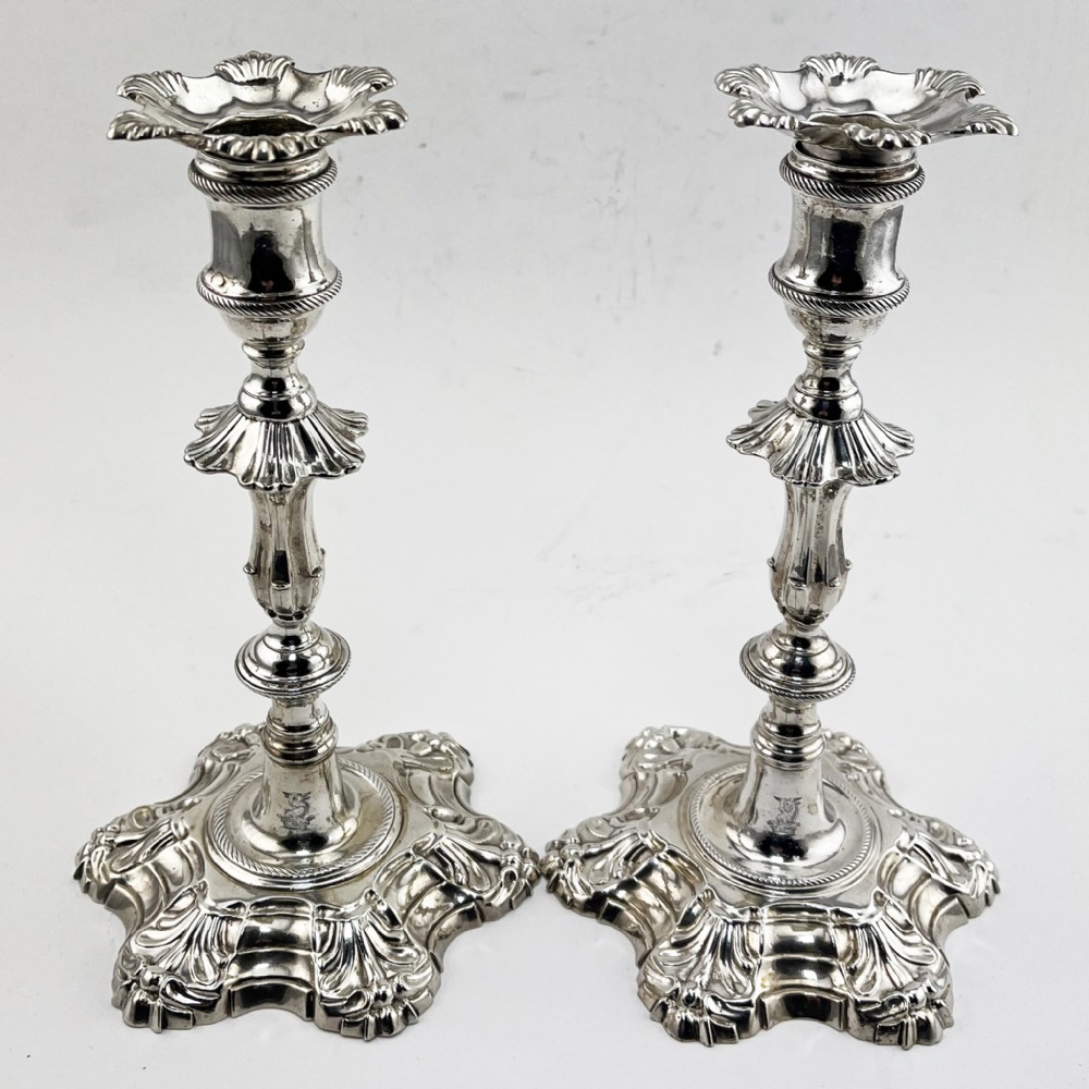 A pair of cast sterling silver George II candlesticks with shell-detailed bases and knopped stems.