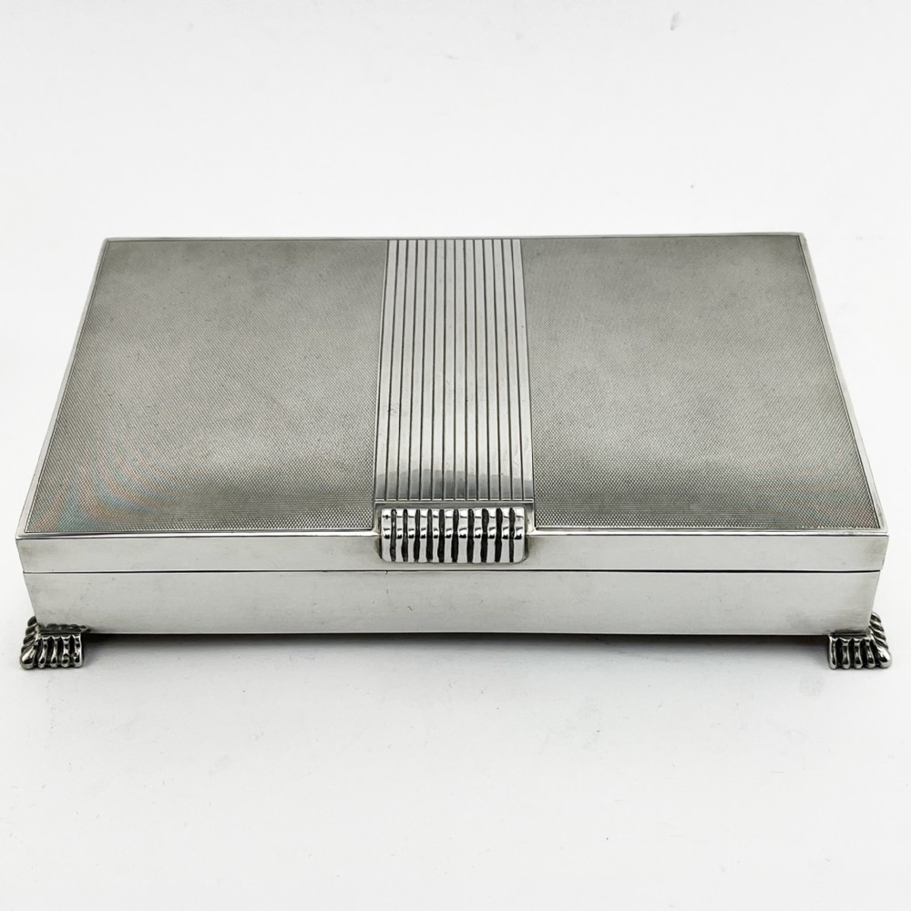A rectangular sterling silver Art Deco box featuring engine-turned panels, a central vertical ribbed band, and ribbed corner feet.
