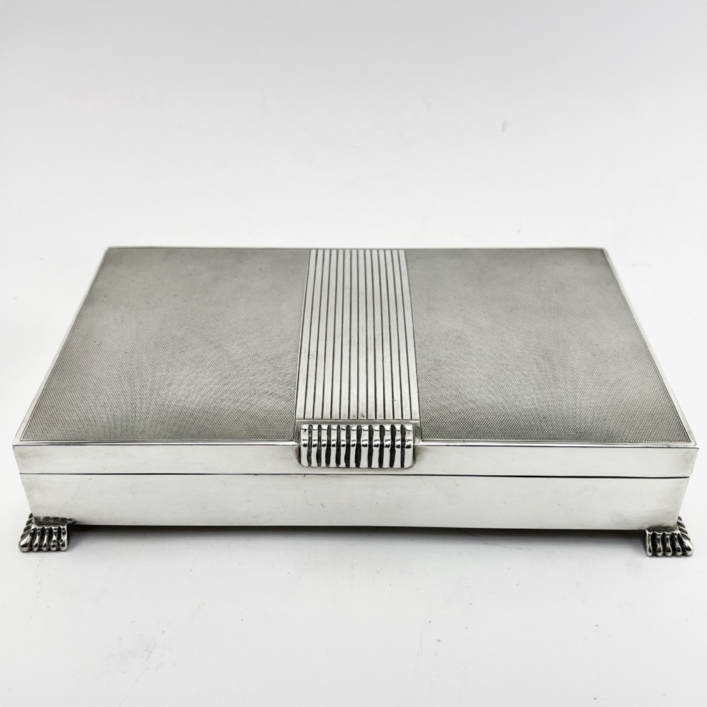 A rectangular sterling silver Art Deco box featuring engine-turned panels, a central vertical ribbed band, and ribbed corner feet. View II